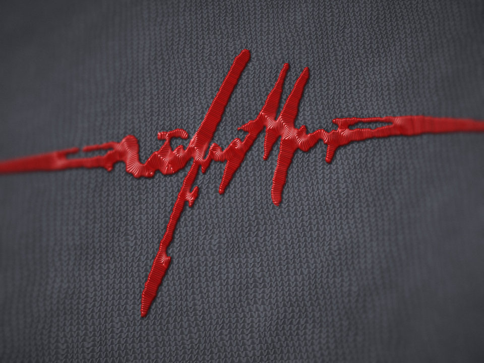 The heartbeat signal in raised red stitching on grey knit